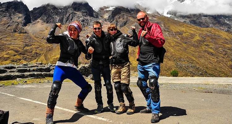 Un grupo de personas posando enérgicamente con un paisaje montañoso de fondo.