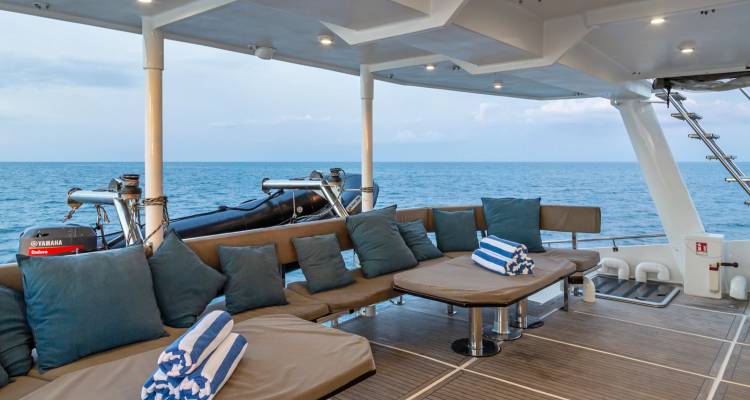 Vaste zone de détente rembourrée sur le pont du yacht avec panorama sur la mer.