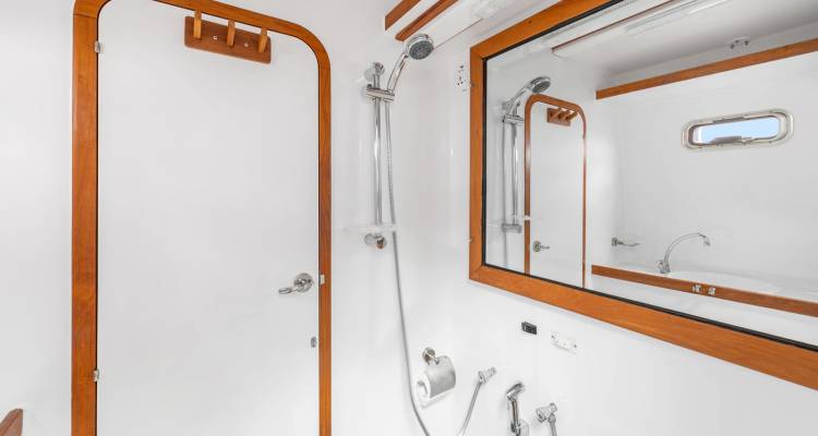 Salle de bains compacte du yacht avec douche et grand miroir.