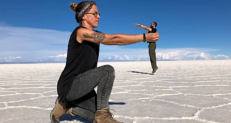 Toma de perspectiva creativa de una persona que parece estar siendo sostenida en las manos de otra en un salar.