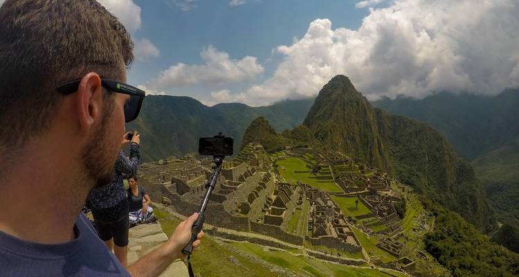 Turista tomándose una selfie con las ruinas de Machu Picchu.