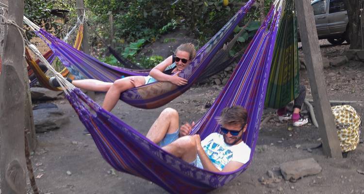Two people relaxing in colorful hammocks outdoors.