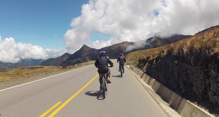Cyclists on a mountain road with scenic views.