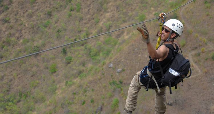 Person zip-lining over a green landscape.