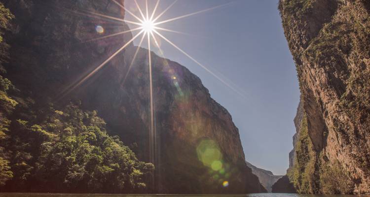Dramatische Schlucht mit Sonnenstrahlen über aufragenden Klippen und Fluss darunter, wahrscheinlich der Sumidero Canyon.