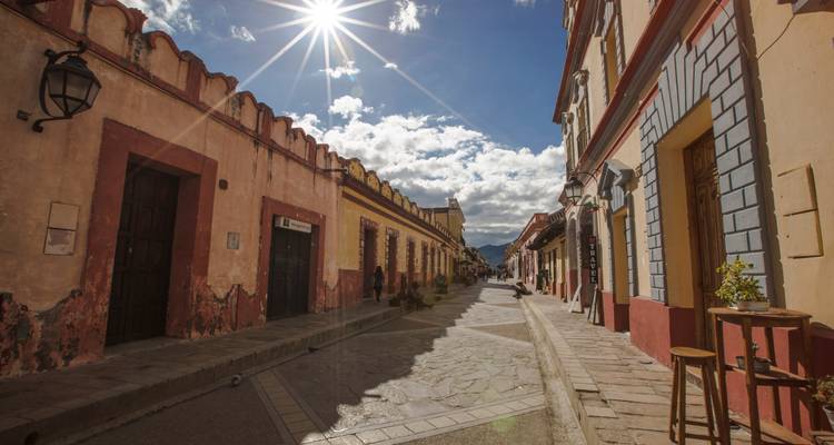 Kopfsteinpflaster-Kolonialstraße in San Cristóbal de las Casas mit pastellfarbenen Gebäuden und starkem Sonnenlicht.