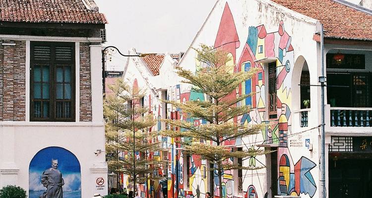 Bâtiments avec des fresques colorées et une rue bordée d'arbres.
