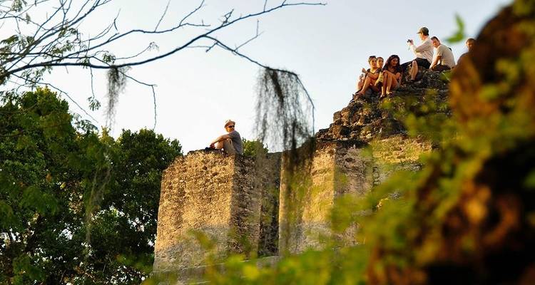 Personas sentadas en una ruina maya.
