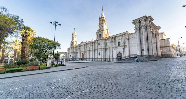 De indrukwekkende witte stenen gevel van de Basilica Cathedral van Arequipa siert een stil plein met kinderkopjes in het zachte ochtendlicht.