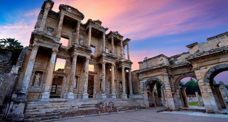 La façade de la bibliothèque de Celsus à Éphèse contre un ciel coloré.