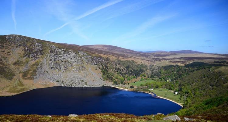Lac de montagne entouré de collines et de forêts par une journée ensoleillée.