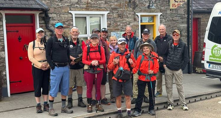 Hikers posing in front of a traditional stone building with red doors.