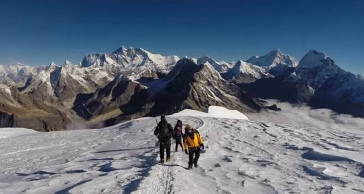 Randonneurs marchant sur un sentier de montagne enneigé avec des vues panoramiques.