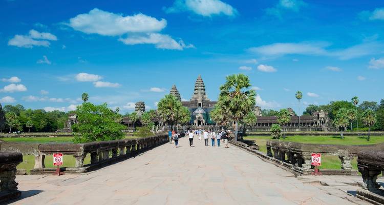 Tourists walking towards Angkor Wat on a sunny day.