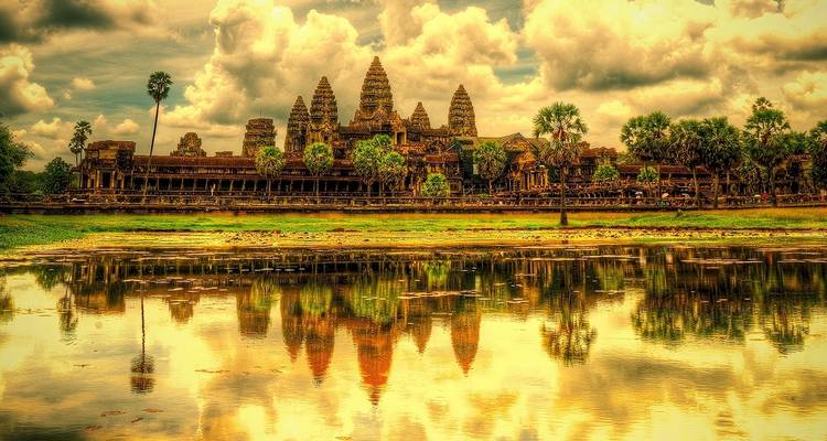 Temple d'Angkor Vat se reflétant dans un étang sous un ciel dramatique.