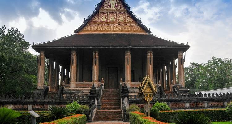 Un grand temple avec de nombreuses colonnes et un jardin luxuriant.