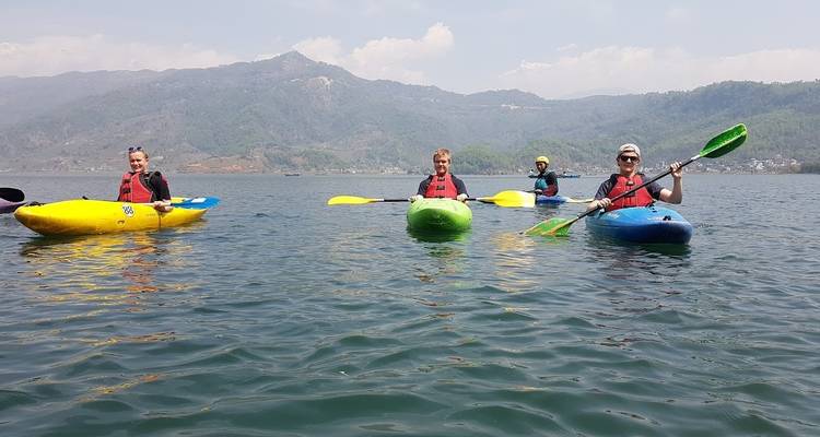 Group of people kayaking in a lake surrounded by mountains.