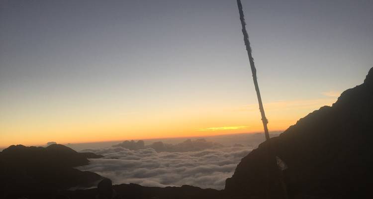 Vue du coucher de soleil sur une vallée remplie de nuages.