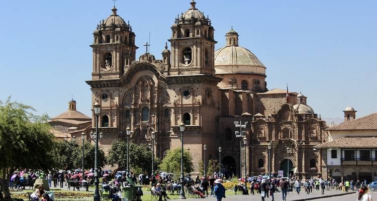 Facade of a historic church with a bustling square in front.