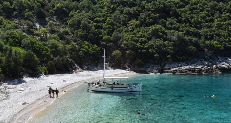 Barco en una playa despejada con colinas boscosas.