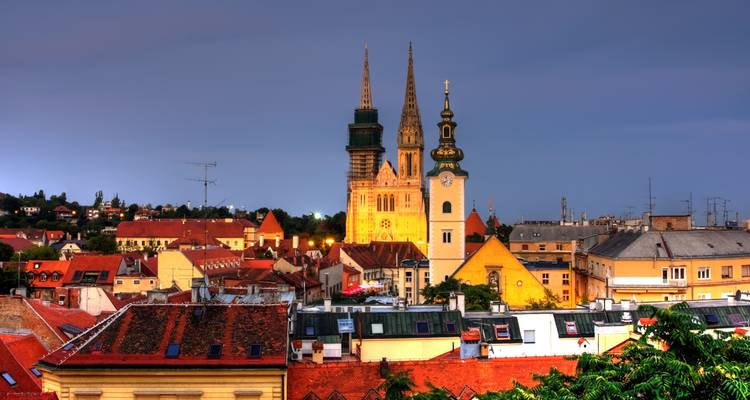 Vista aérea de Zagreb con las torres de la catedral iluminadas al anochecer.