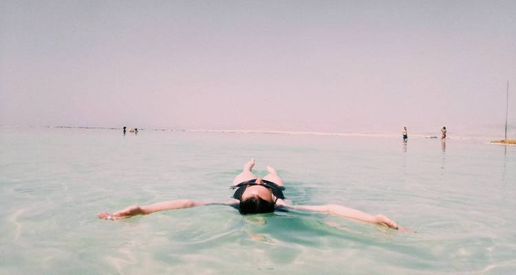 Femme flottant sur le dos les bras écartés dans les eaux calmes de la mer Morte.