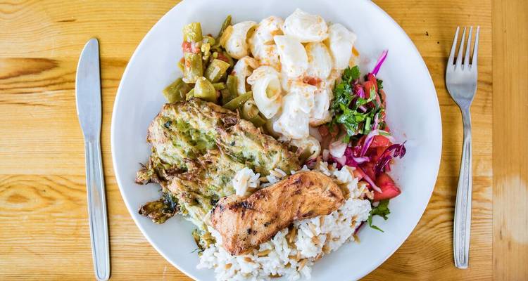 Close-up of a Turkish plate featuring grilled chicken, rice, vegetables and salad on a wooden table