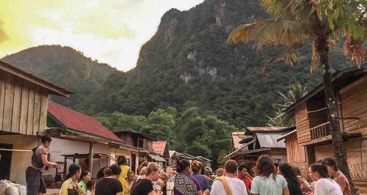 Gente reunida en el entorno de un pueblo con montañas al fondo.