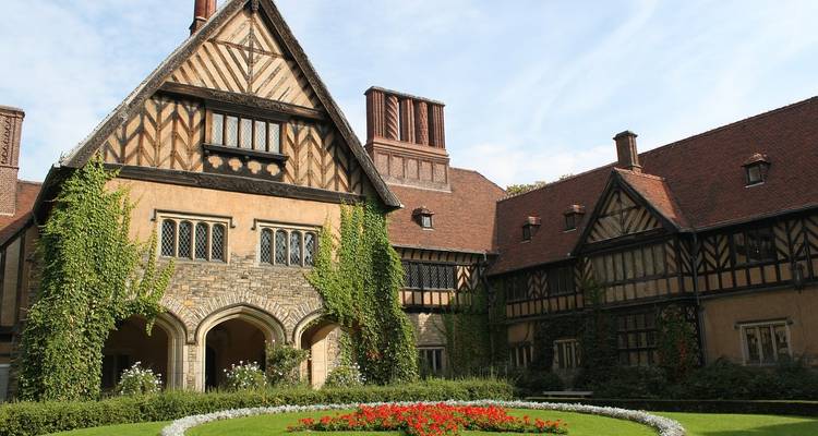 Half-timbered landhuis met klimop begroeide muren en een bloemrijke ronde grasveld.