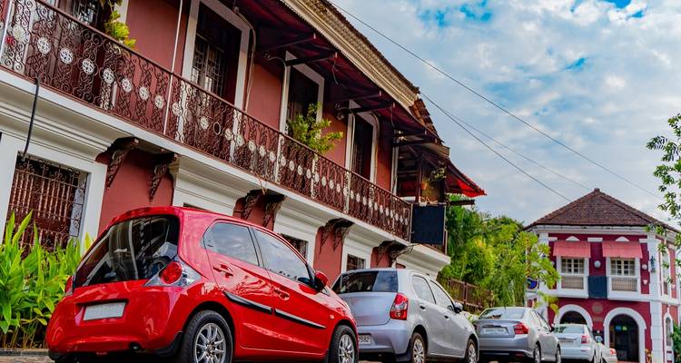 Bâtiment coloré de style portugais avec des voitures garées dans une rue