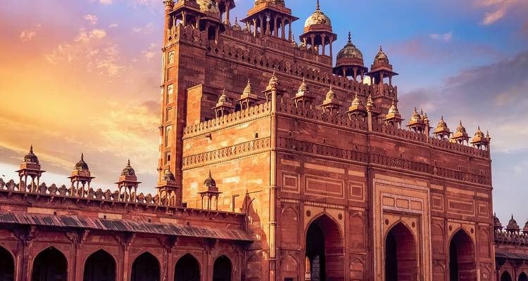 Fort historique avec de grandes arcades et des dômes au coucher du soleil.