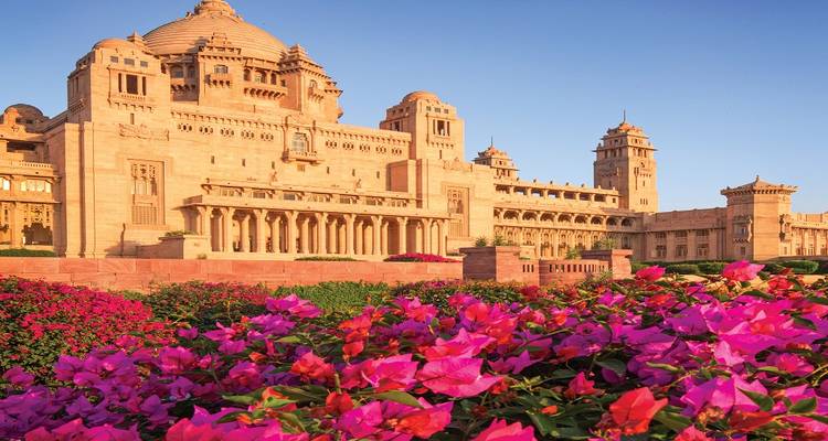 Majestic building with a garden and vibrant flowers in the foreground.