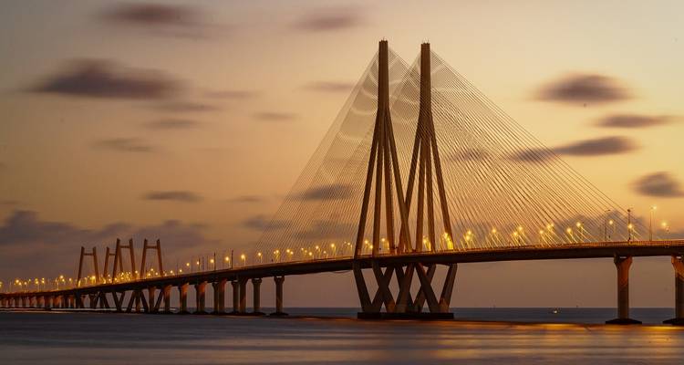 Large bridge over water at sunset, with modern design and glowing lights.