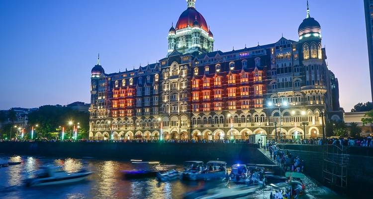 Iconic hotel building illuminated at night with boats on the water.