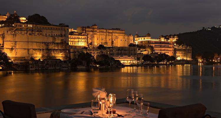 A riverside palace lit up at night with an elegant dining setup.