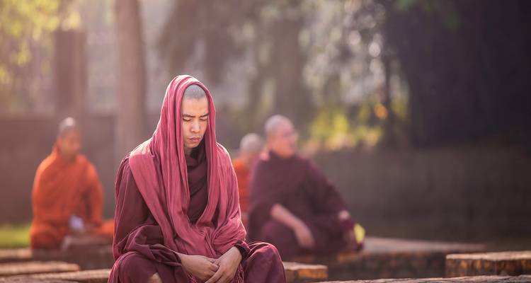 Monks in traditional attire meditating outdoors.