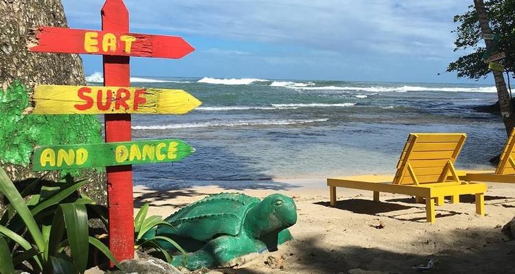 Cartel en una playa promocionando actividades con el océano de fondo.