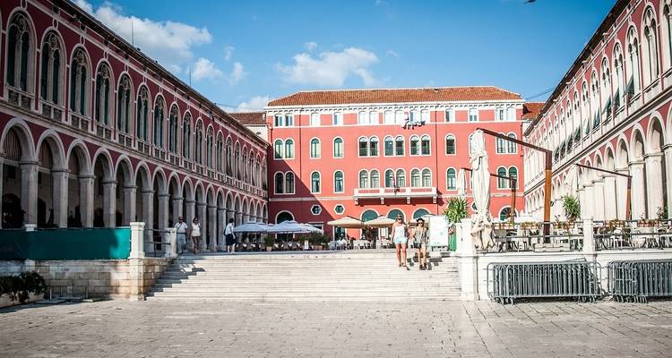 Una plaza espaciosa con edificios coloridos y un ambiente animado de cafeterías.