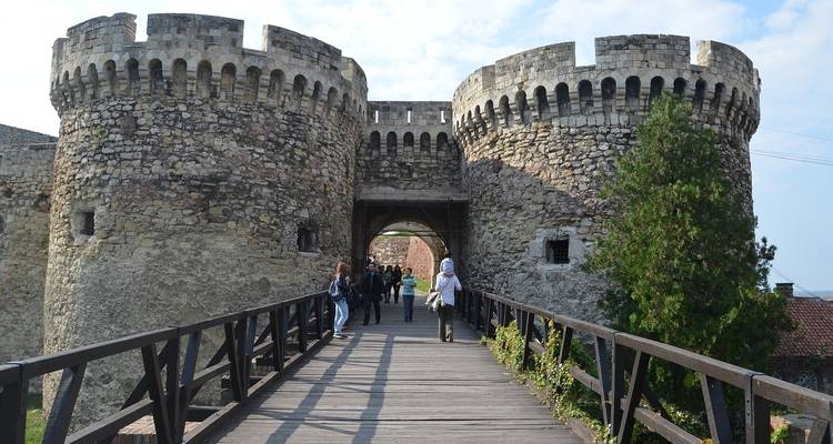 Una fortaleza histórica de piedra con visitantes explorando el área.