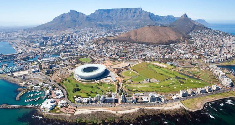 Luftaufnahme von Kapstadt mit einem Stadion, dem Ozean und dem Tafelberg.