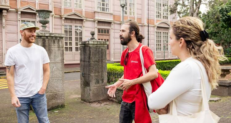 Kleine groep die praat voor een historisch roze gebouw en stenen zuilen in San Jose