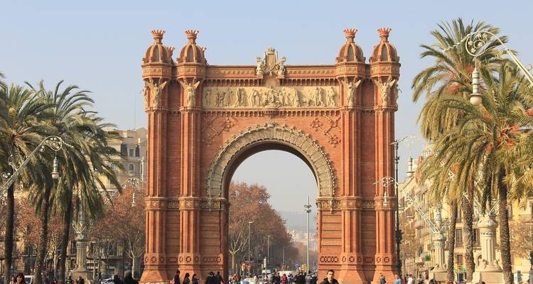 The Arc de Triomf with people in front, set in a palm tree-lined street in Barcelona.