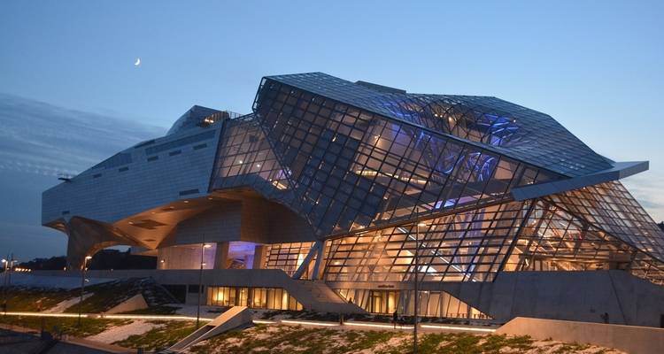 Un bâtiment moderne en verre illuminé au crépuscule.