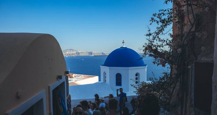 Rue bondée avec la célèbre église au dôme bleu à Santorin.