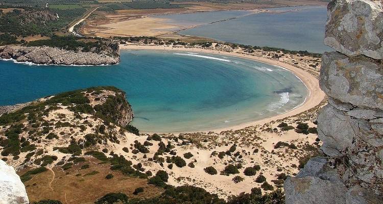 Vista aérea de una playa en forma de media luna con agua cristalina.