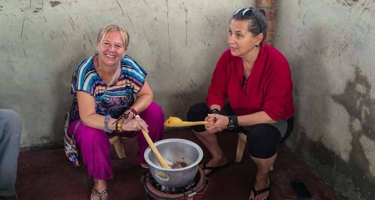 Two women cooking together, smiling at the camera.