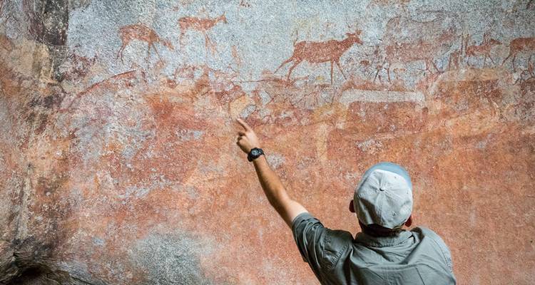 Personne pointant du doigt de l'art rupestre ancien représentant des animaux.