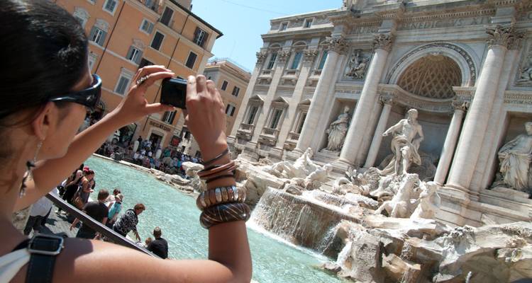 Viajero fotografiando la Fuente de Trevi con una multitud reunida alrededor de la piscina turquesa