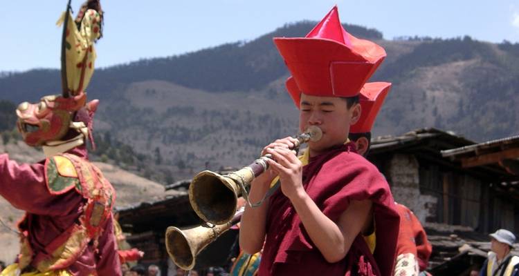 Traditionally dressed people performing a cultural ritual with instruments.