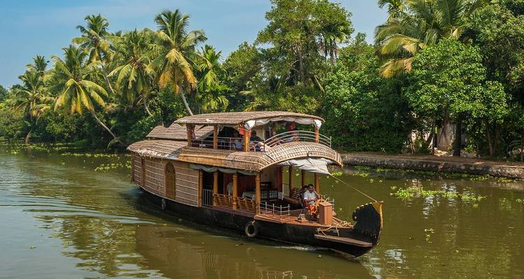 Casa flotante deslizándose por un río sereno bordeado de palmeras.